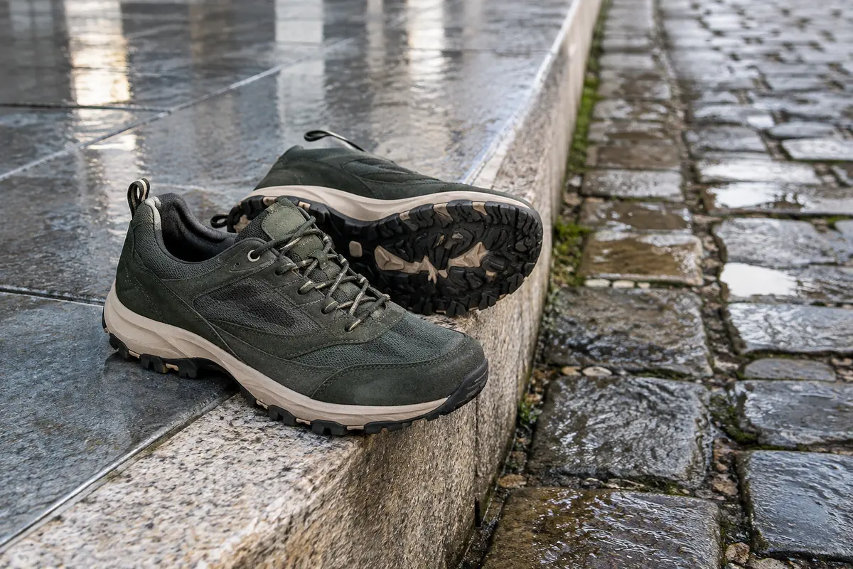 Semelle de chaussure urbaine près de pavés et d’un trottoir humide aux surfaces contrastées